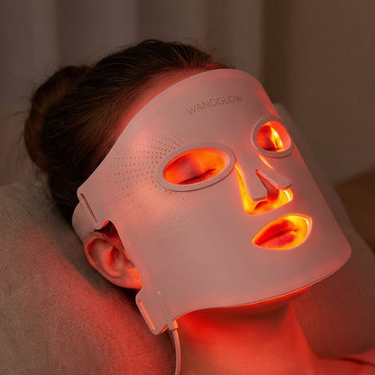 Person wearing a LED face mask with red light therapy on a neutral background