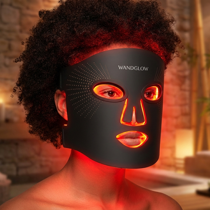 Person wearing a black LED face mask with visible brand 'Wandglow' in a warm-toned indoor setting.