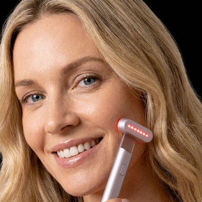 Woman using a facial massager with visible LED lights on a black background
